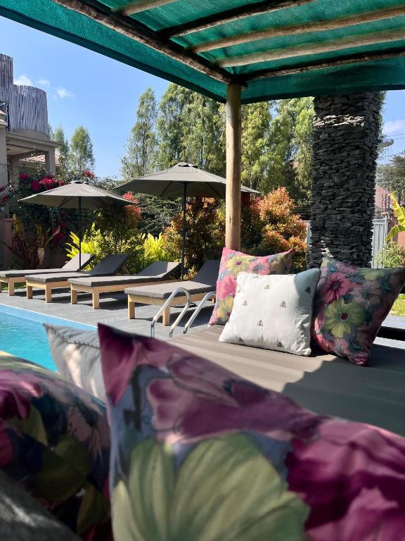 a bed with pillows next to a pool with umbrellas at Marini Ndoto in Themi