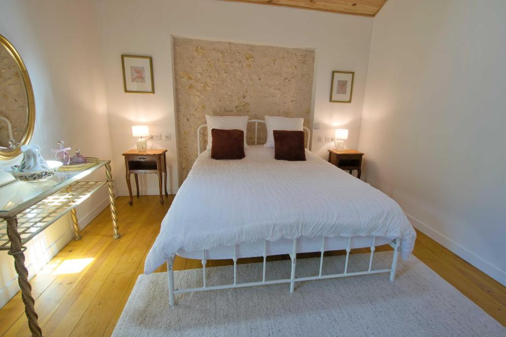 a bedroom with a white bed with two tables and a mirror at The Lodge Gite 3 Star in Saint-Privat-des-Prés