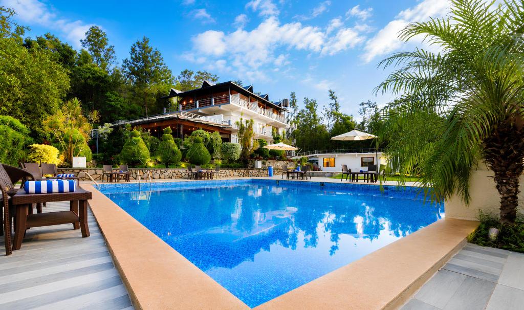 a large swimming pool in front of a house at The Blossom Resort - Chikmagalur in Chikmagalūr
