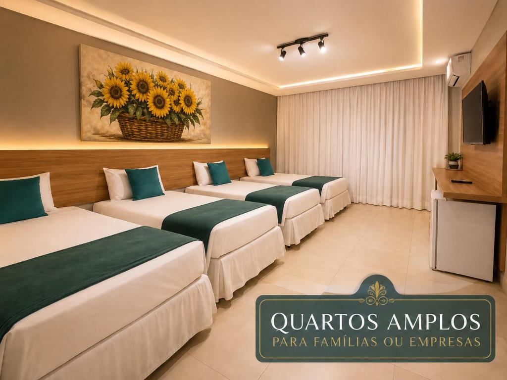 a row of beds in a hotel room at Hotel Cantinho Verde in Teixeira de Freitas