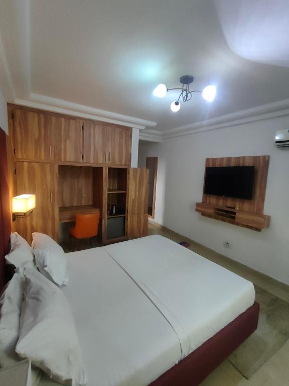 a bedroom with a large white bed and a flat screen tv at Résidence New Land Sarl in Douala