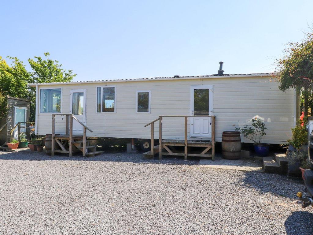 a white house with a porch and stairs on it at The Lodge Caravan Rental in Amlwch