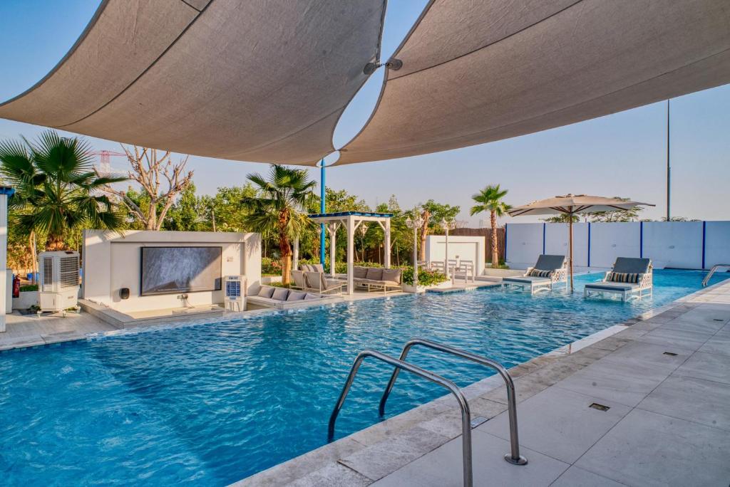 a swimming pool with chairs and a large umbrella at Santorini check in in Ras al Khaimah
