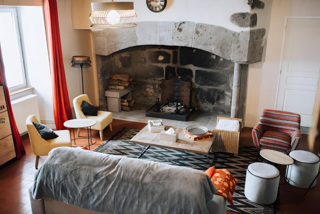 a living room with a stone fireplace and a couch at Le nid du Randonneur in Marmanhac