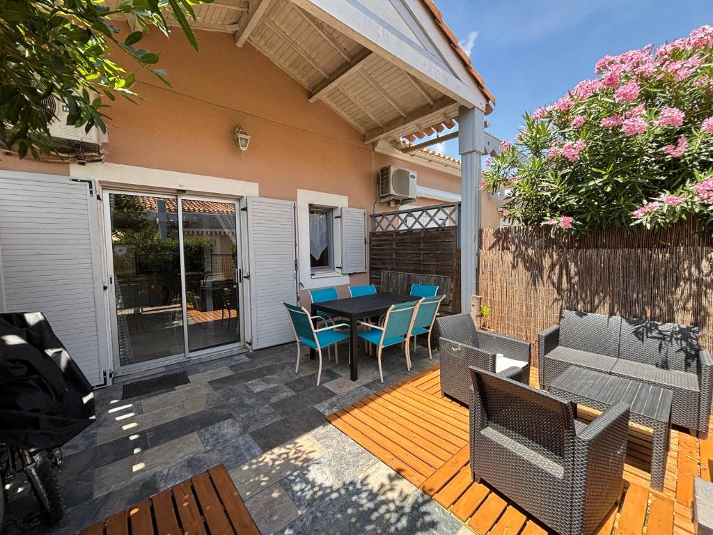a patio with a table and chairs on a deck at Janislove34 Maison 1 Chambre avec accès piscine dans résidence à Palavas les flots in Palavas-les-Flots