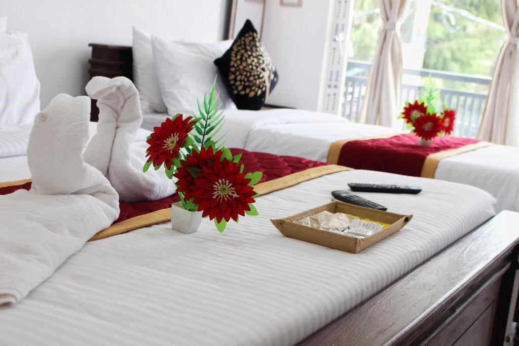 a room with two beds and a tray with flowers on it at Altiora Homestay in Kodaikānāl