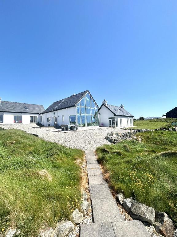 a house with glass windows on top of a field at Doleen Quay House in Ballyconneely
