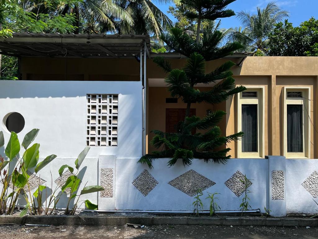 a house with a white fence in front of it at Sanghiang Homestay in Batukaras