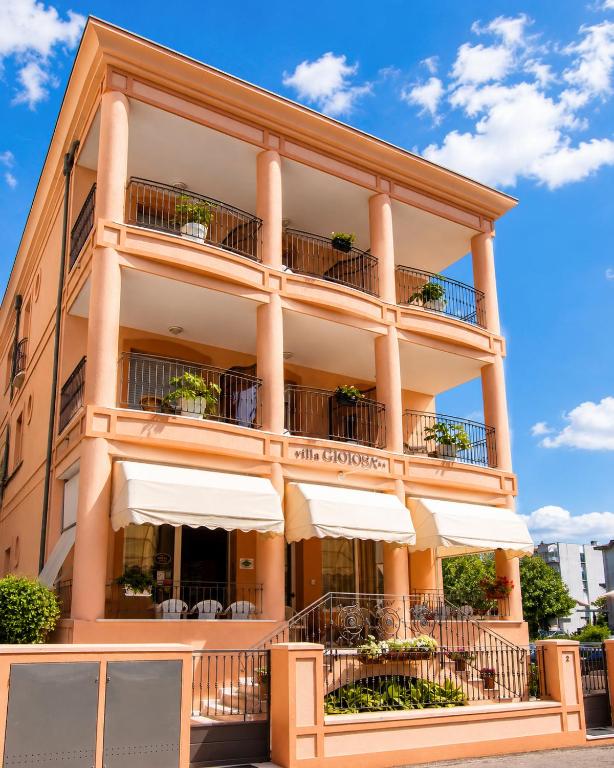 a tall building with white umbrellas at Hotel Villa Gioiosa - Beach & Bistrot in Rimini