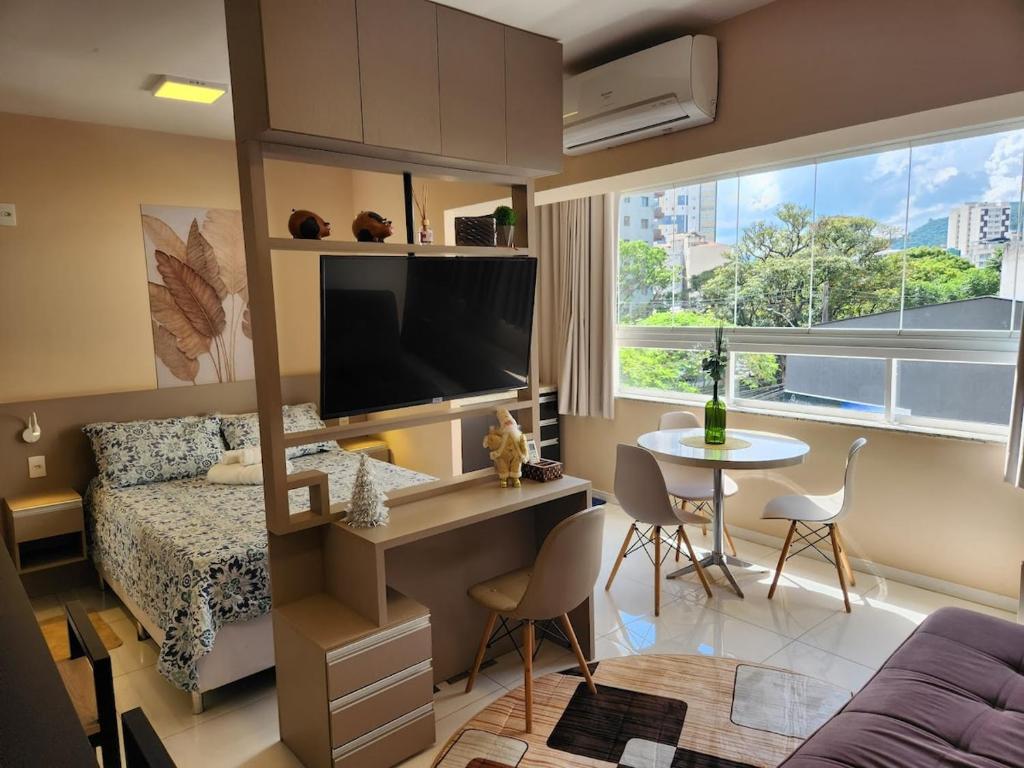 a bedroom with a bed and a desk with a tv at Lindo Studio no Centro de Poços de Caldas in Poços de Caldas