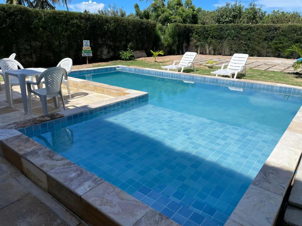 a swimming pool with chairs and a table in the middle at Casa da GabiLu in Itapipoca