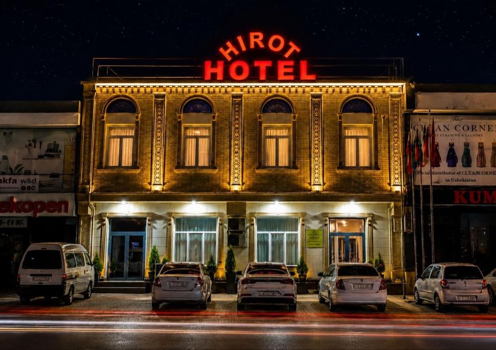a hotel with cars parked in front of it at night at Hotel Hirot in Tashkent