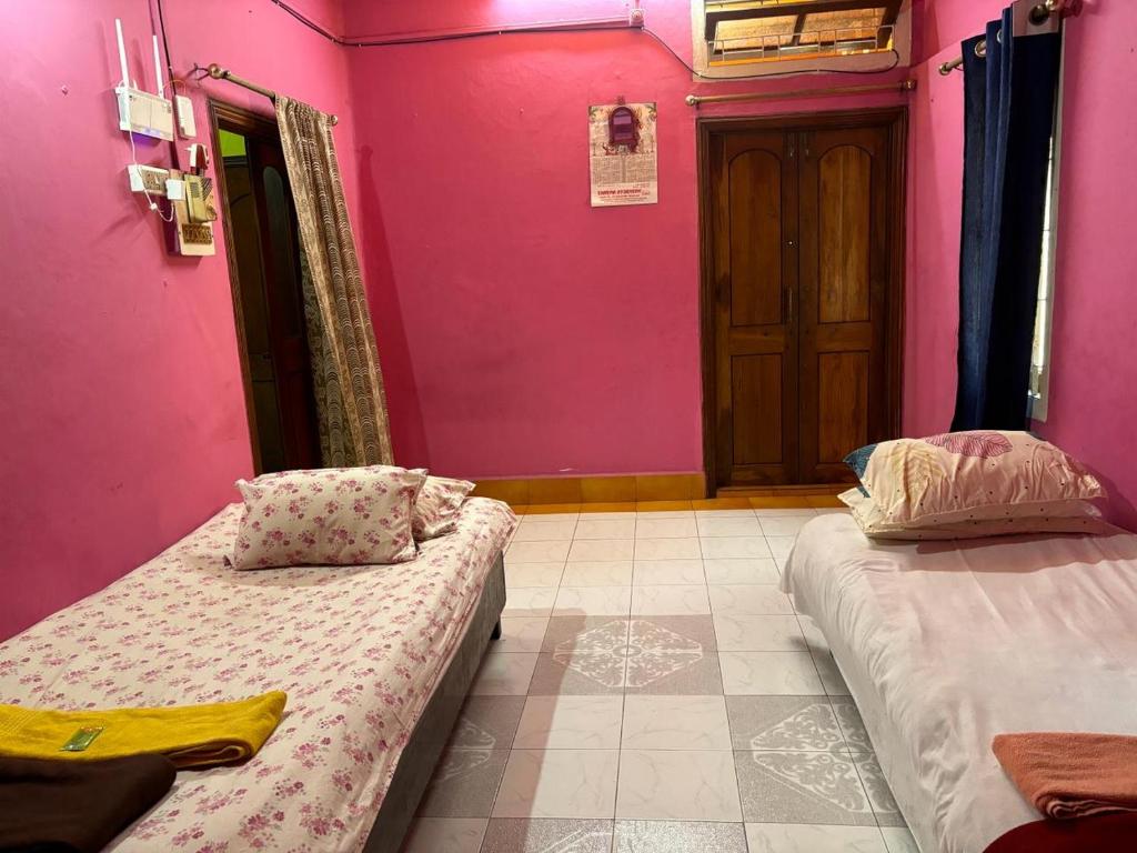 a room with two beds and a pink wall at Real City Homestay in Guwahati
