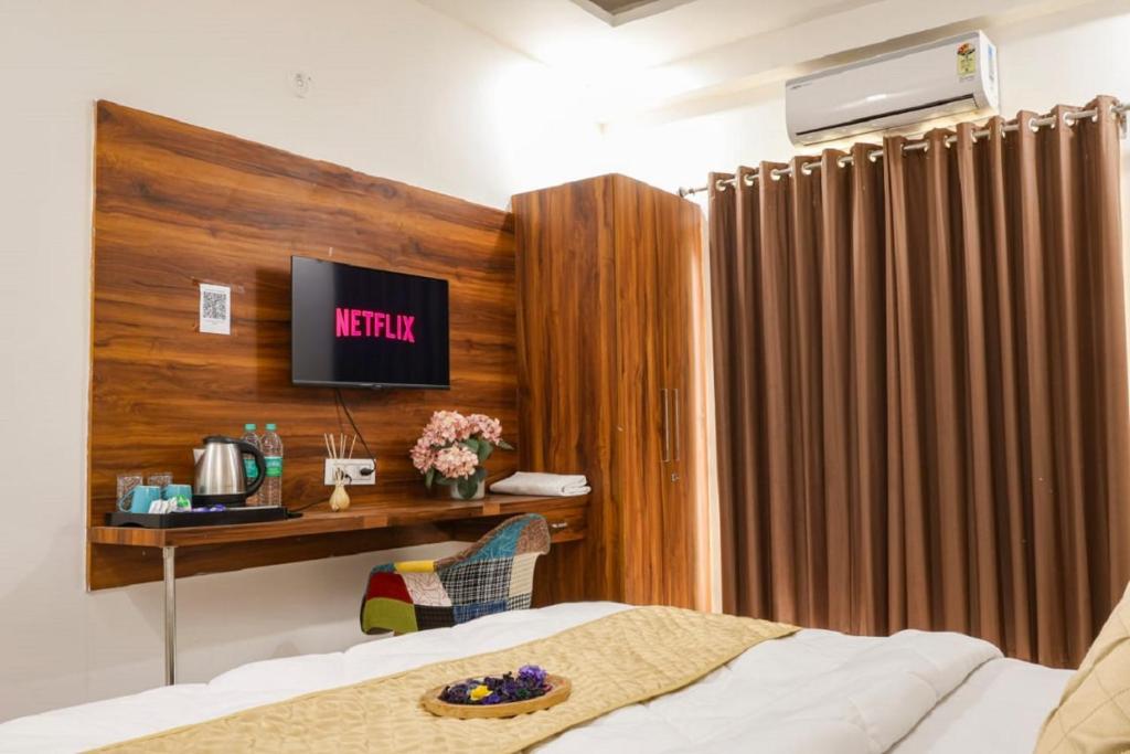 a bedroom with a bed and a tv on a wall at Coco House in Greater Noida
