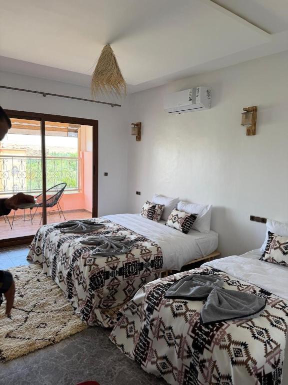 a bedroom with two beds and a balcony at Qamar Mgouna Hotel in El Kelaa des Mgouna