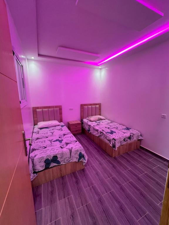 two beds in a room with purple lights at costa in Oued Laou