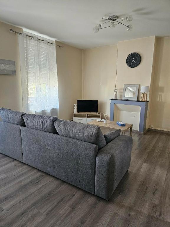 a living room with a couch and a table at Les Trésors à 2 pas du Pal in Dompierre-sur-Besbre