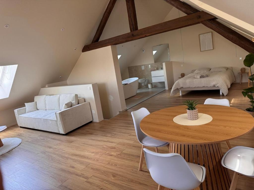 a living room with a table and a bed at Sous les combles in Hambach