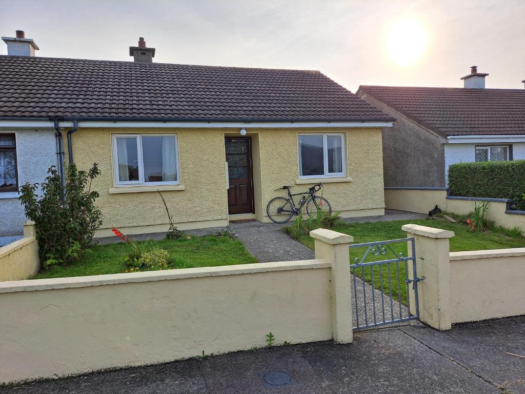 a yellow house with a fence in front of it at Sunrise House in Cahersiveen