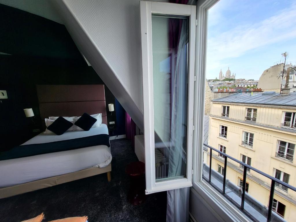 a bedroom with a bed and a large window at Accueil Hôtel Paris Pigalle Montmartre - Hôtel rénové in Paris