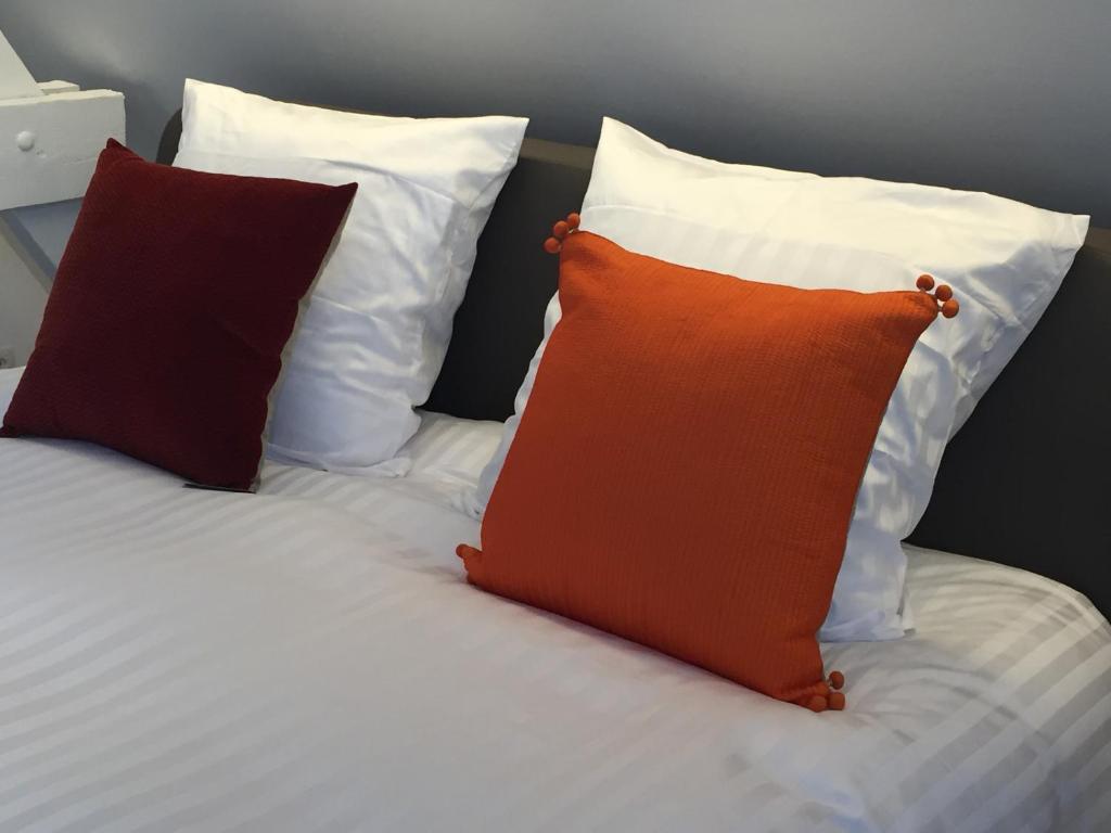ブルージュにあるB-Squareの白枕付きベッドの上にオレンジ色の枕