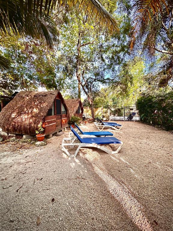 two lounge chairs and a hut with a thatch roof at Cabañitas y Dorms in Bacalar