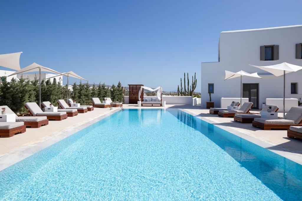 a swimming pool with lounge chairs and umbrellas at 18 Grapes Hotel in Agios Prokopios