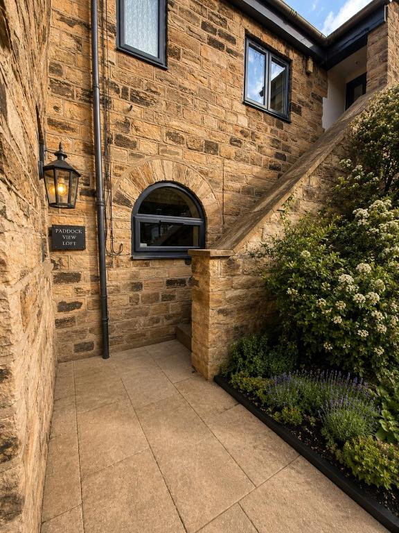 a walkway leading to a brick building with a window at Paddock View Loft Countryside Retreat in Thornhill