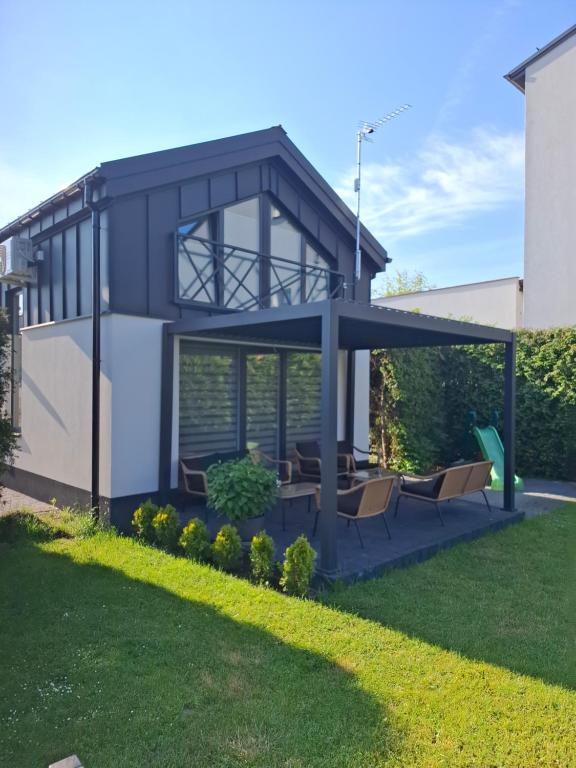 a house with a blue roof with chairs in a yard at TINY HOUSE domek do wynajęcia in Olsztyn