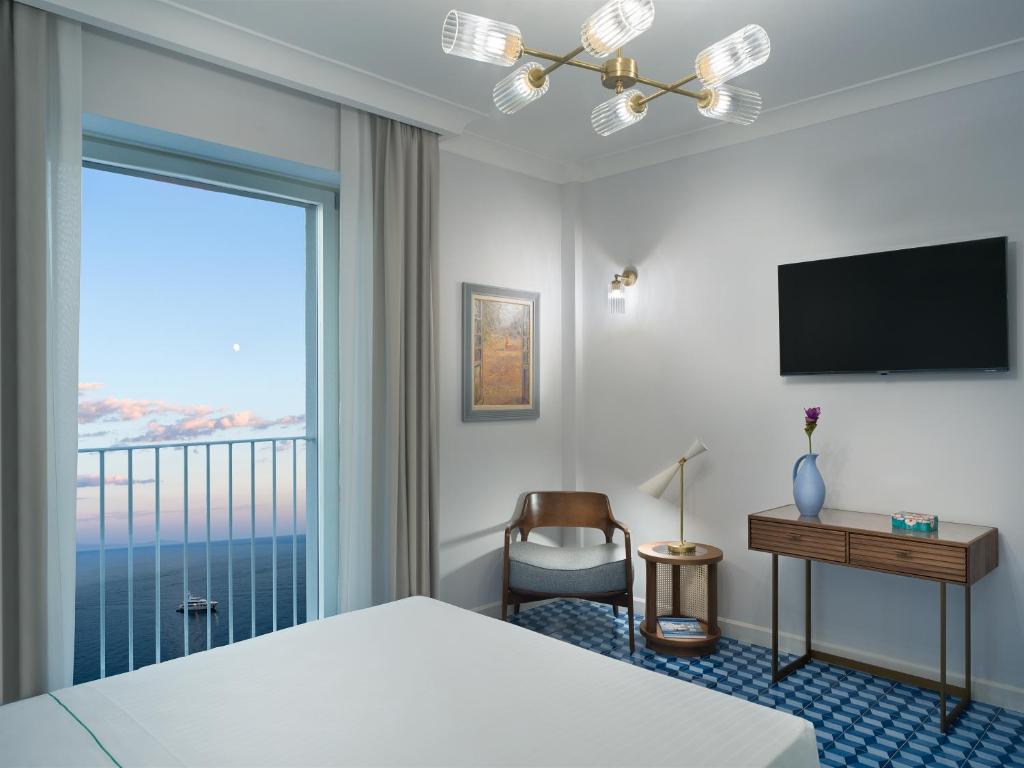 a hotel room with a bed and a large window at Il Tipografo di Amalfi A Family Museum Hotel in Amalfi