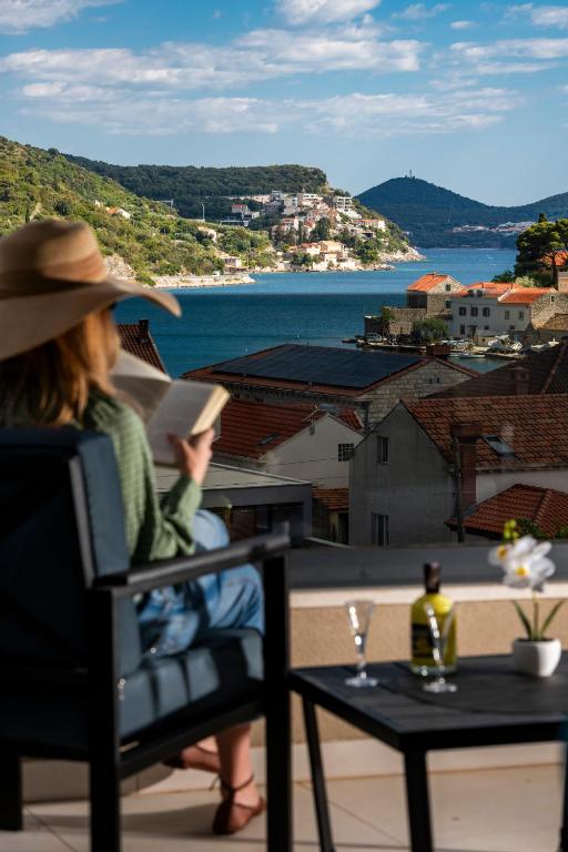 a woman sitting in a chair reading a book on a balcony at Alba Azzura in Zaton
