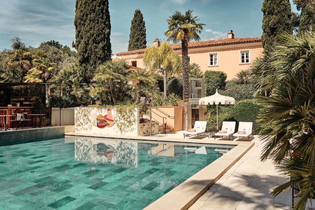 a pool in front of a house with palm trees at La Bastide de Saint Tropez in Saint-Tropez