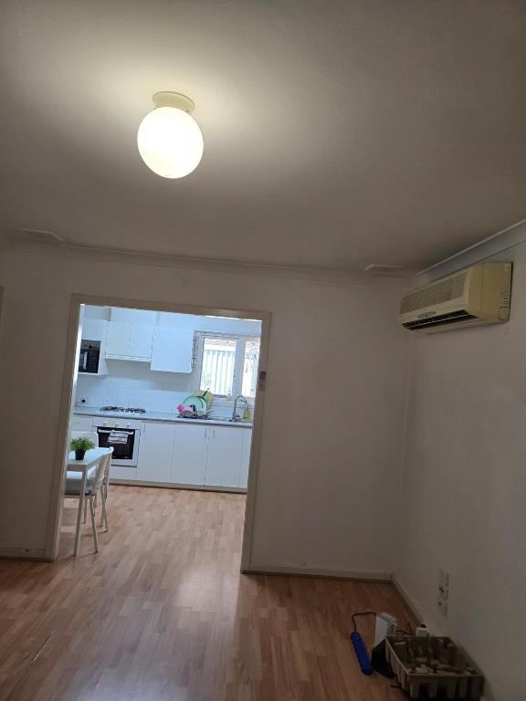 an empty living room with a kitchen and a table at Girrawheen3 - Room in a Shared House in Perth