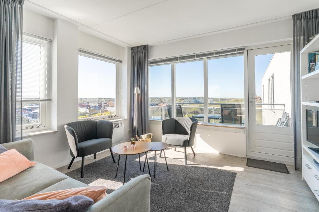 a living room with a couch and chairs and windows at Appartementencomplex Juliana 132 in De Koog