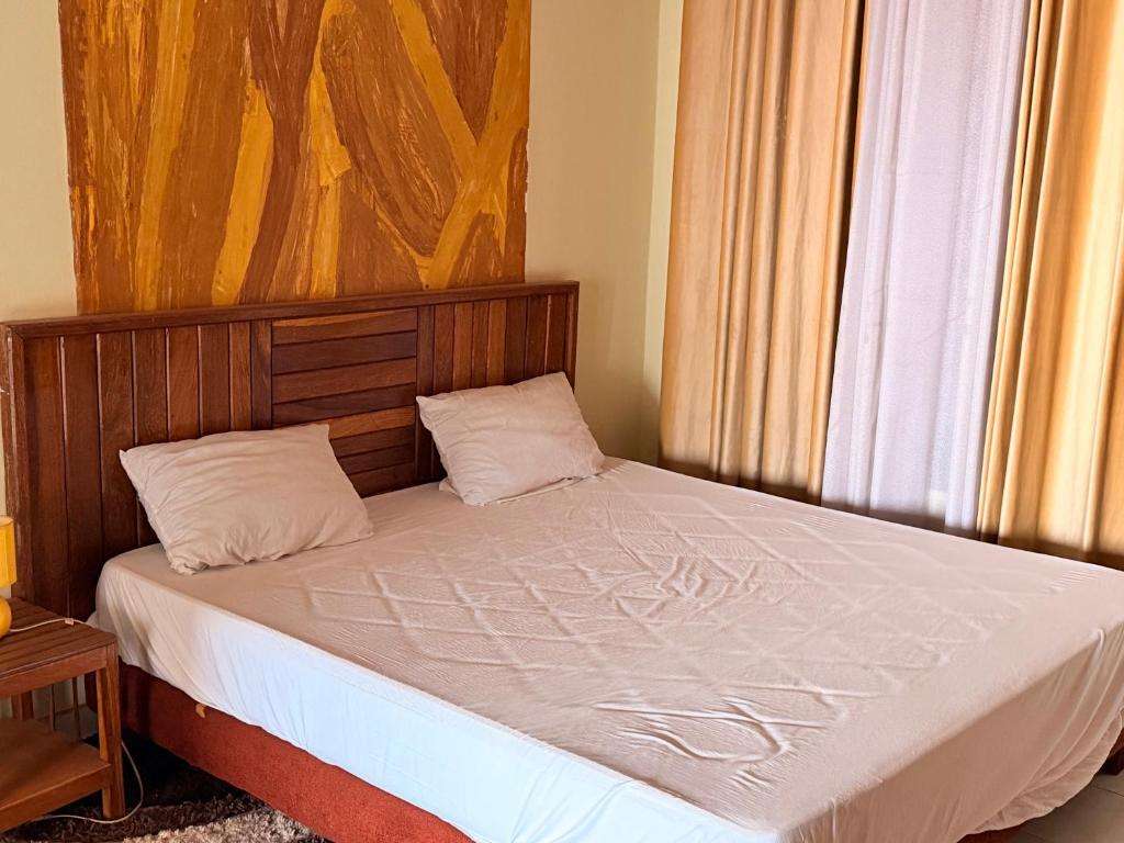 a bed with a wooden headboard next to a window at Fitini appart in Bamako