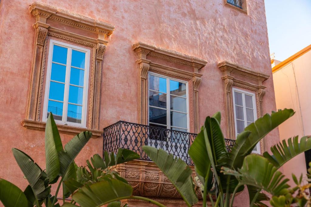 a building with a balcony with windows and plants at Palazzo Venneri Lloyd - Historic Heritage Palazzo in Gallipoli