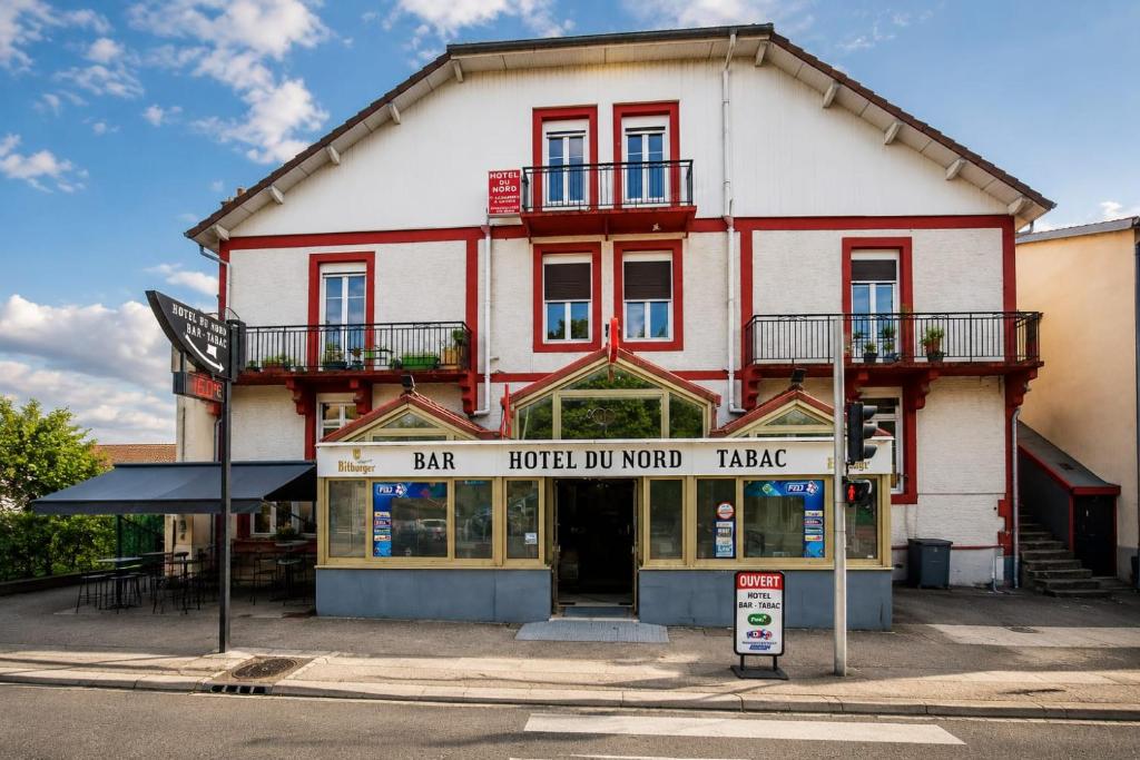 a large red and white building with a store at Hôtel du Nord in Contrexéville