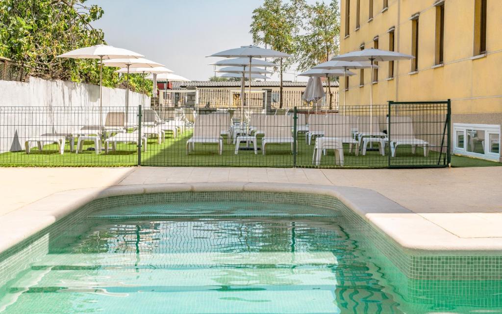 a swimming pool with tables and chairs and umbrellas at Checkin Madrid Móstoles in Móstoles