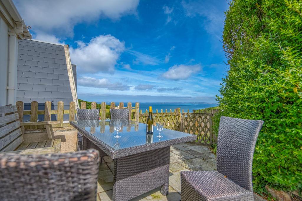 a patio with a table and chairs with a view of the ocean at Heddfan Cottage in Haverfordwest