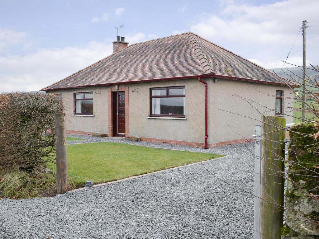 a house with a gravel driveway in front of it at Beuchan Bungalow in Closeburn