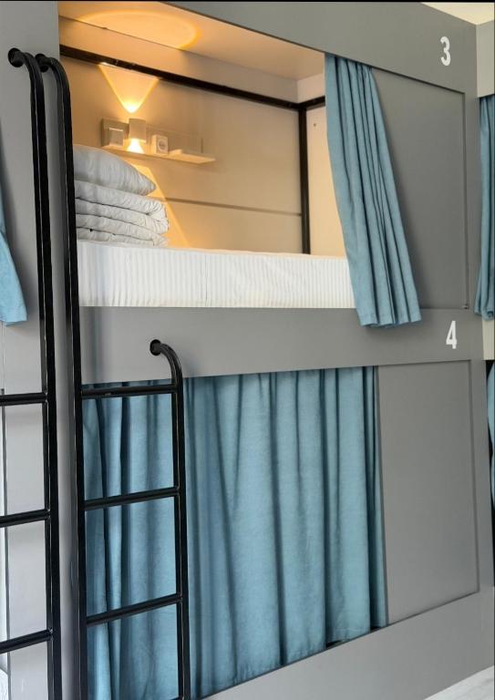 a bunk bed with blue curtains in a room at Deutsch Hostel Osh in Osh