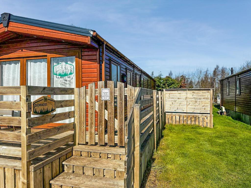a wooden fence in front of a tiny house at Dorado Cottage - Uk49469 in Morpeth