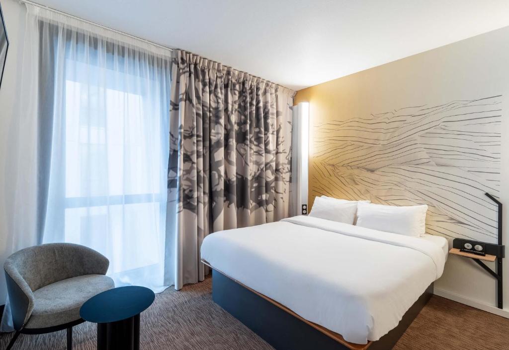 a hotel room with a bed and a chair at B&B HOTEL Lille Villeneuve d'Ascq Grand Stade 3 étoiles in Villeneuve d'Ascq