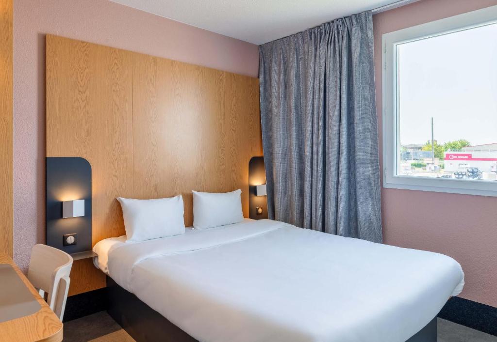 a hotel room with a large bed and a window at B&B HOTEL Lyon Eurexpo Chassieu in Chassieu