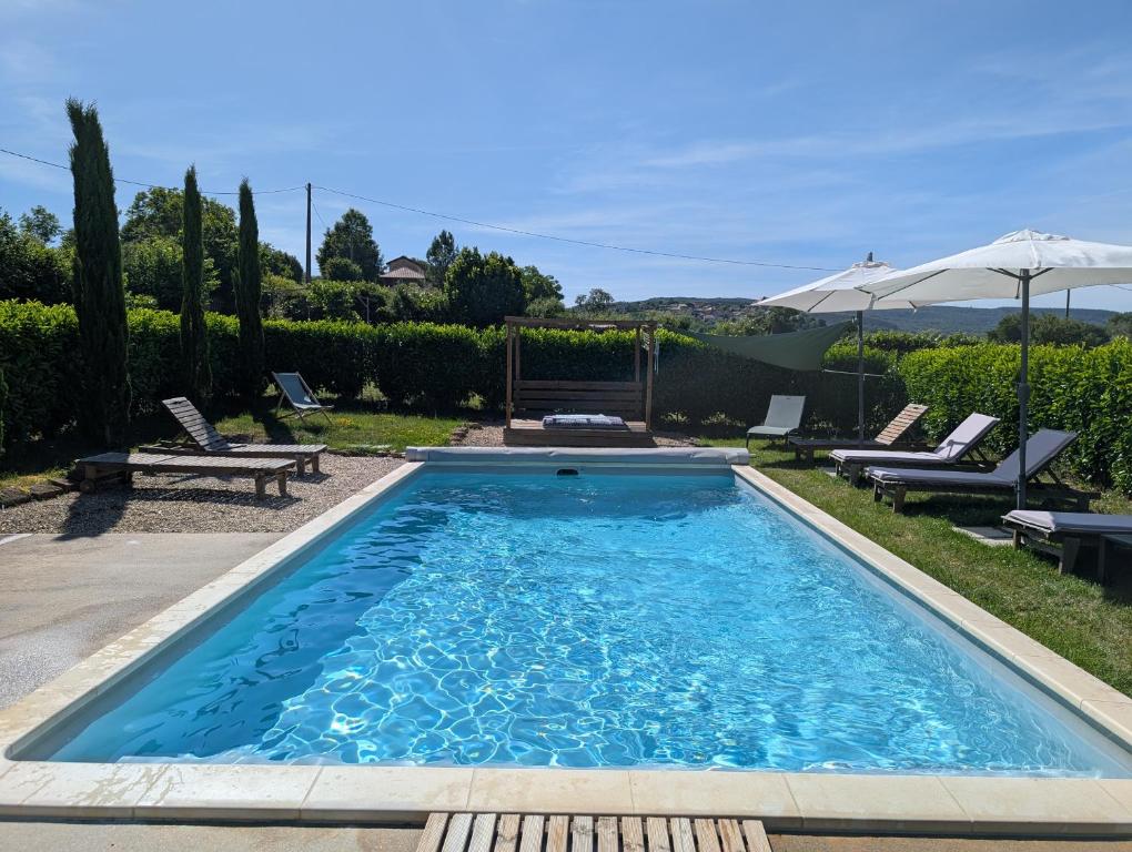 a swimming pool in a yard with chairs and an umbrella at Maison Mazille in Mazille