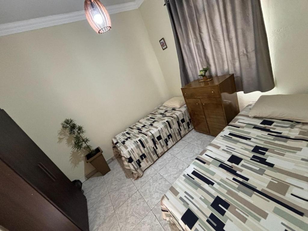 a bedroom with two beds and a dresser and a window at Pousada e Pensionato Consuelo in Montes Claros
