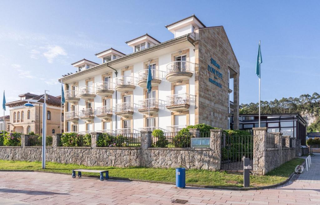 a large white building with a bench in front of it at Hotel Silken Don Pepe y Don Pepe Ría in Ribadesella