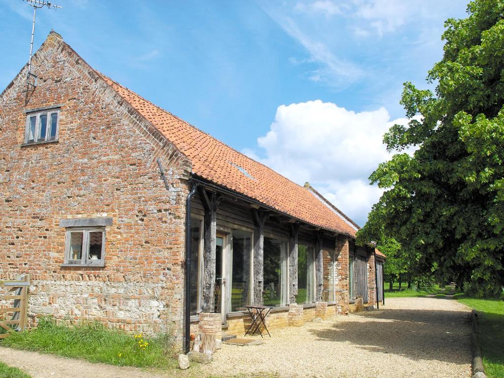 an old brick building with a tree next to it at The Granary in Oxborough