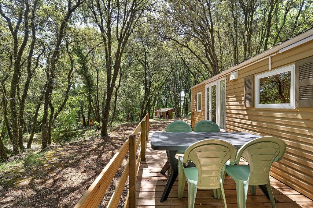 a patio with a table and chairs on a deck at 23.Mobil-home option clim-5pers in Calviac