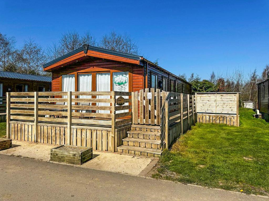 a wooden cabin with a fence in the grass at Toucana - Uk49468 in Morpeth